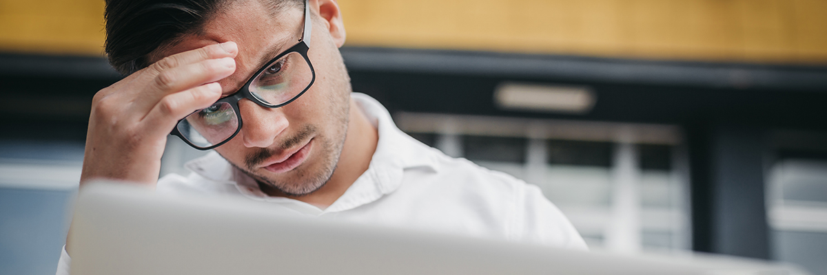 Male anxiously looking at laptop BANNER