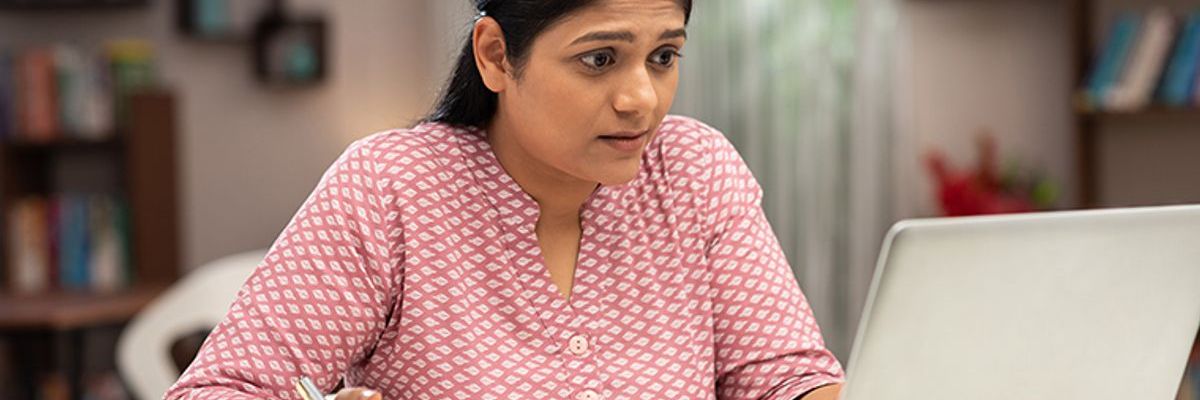 Asian female alarmed working on laptop TAB