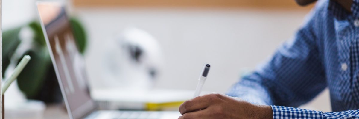 Asian man writing using laptop