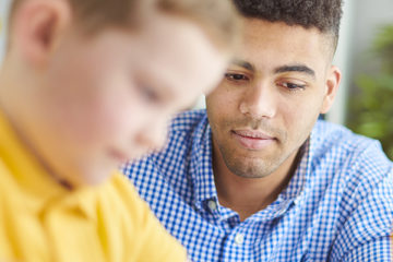 Young mixed race male teacher primary white male pupil