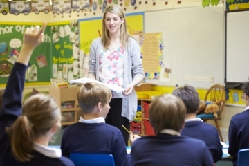 White female teacher standing in front of primary pupils