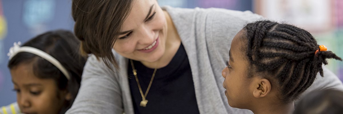 Young white female looking at black primary child
