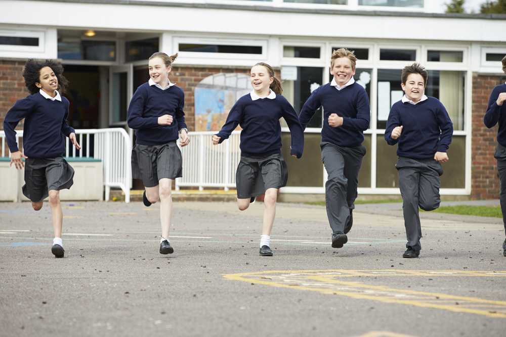 Mixed secondary pupils running in playground